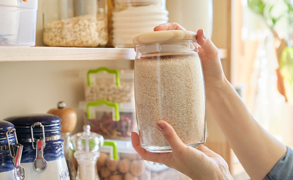 Food products in the kitchen storing ingredients in pantry. Woman taking jar of rice